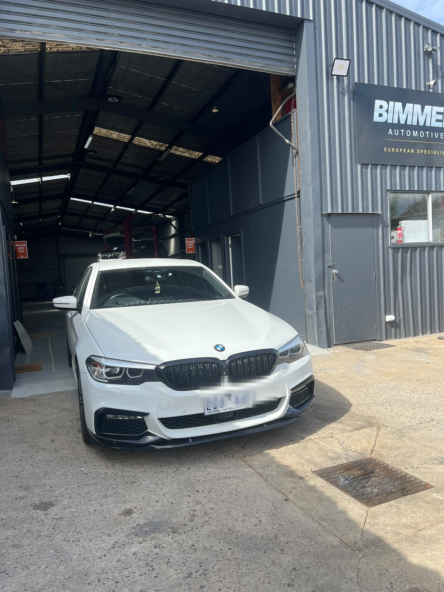 BMW 5 Series arriving at the BIMMER AUTOMOTIVE workshop entrance in Craigieburn