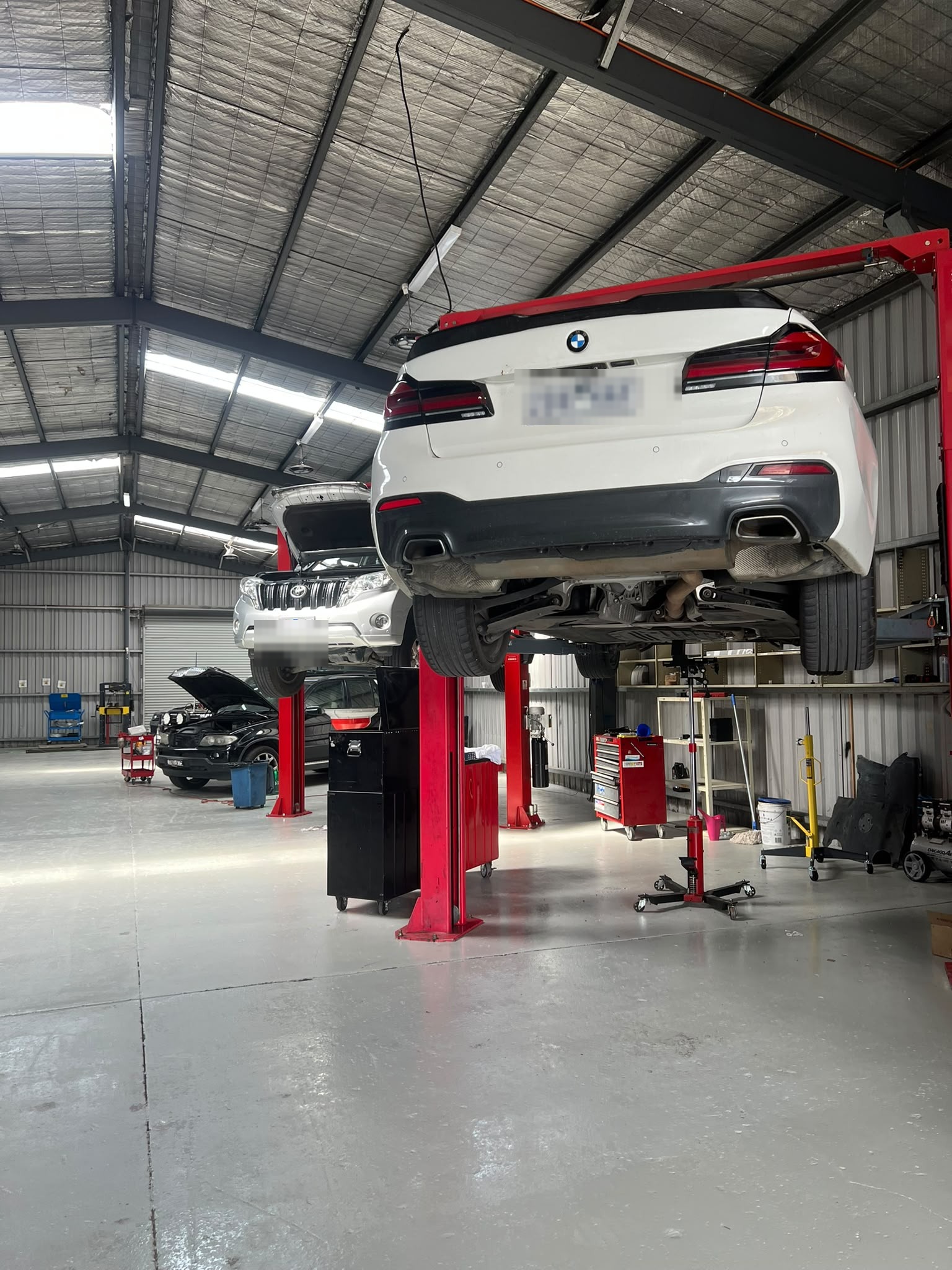 Workshop bay with a BMW, Land Rover and other European vehicles on hoists